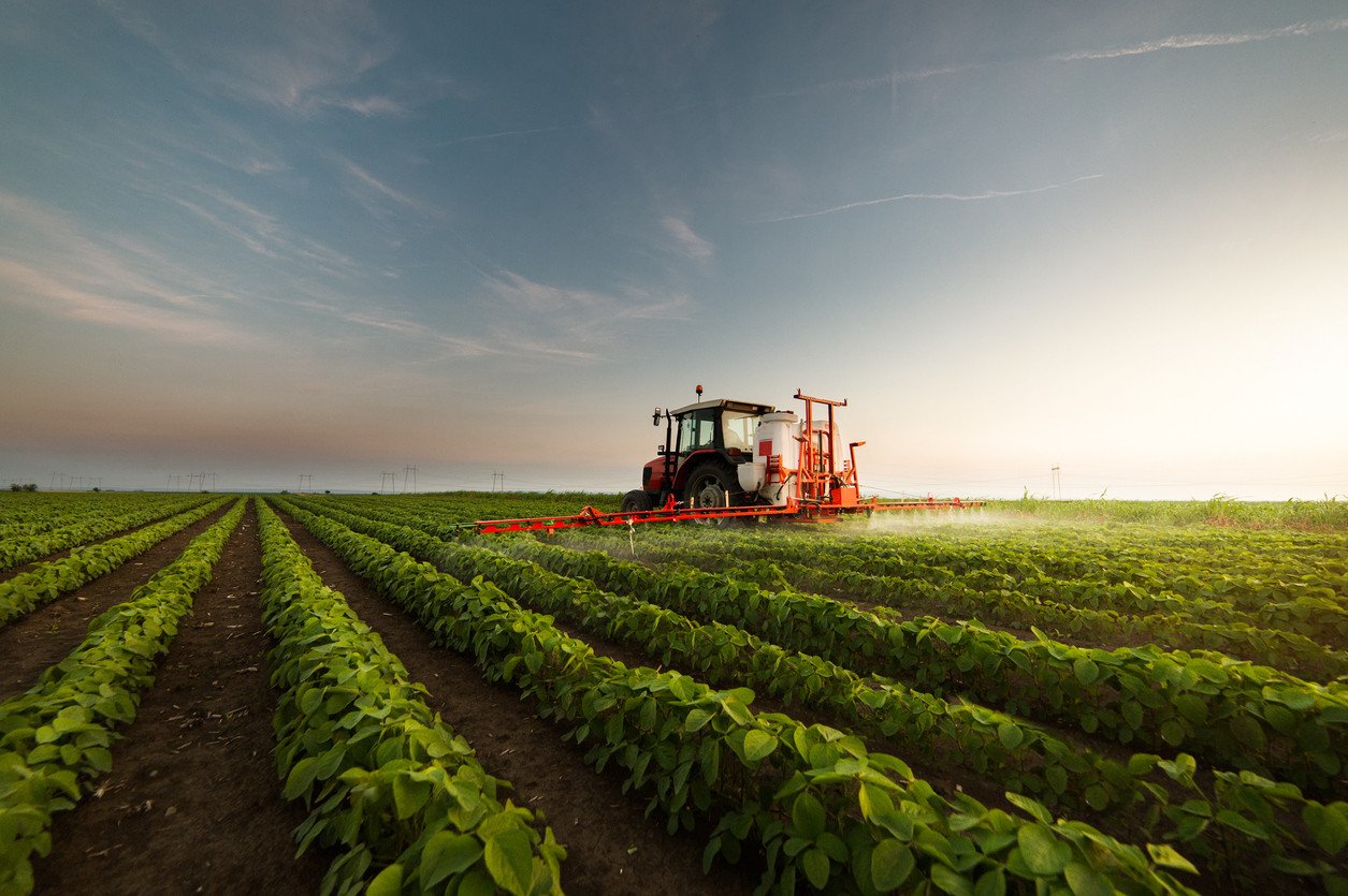 Tractor spraying pesticides on crops